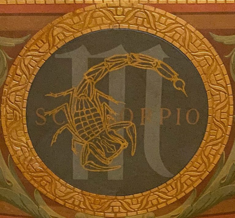 A golden image of a scorpion encircled in bronze, brown and golden hues.